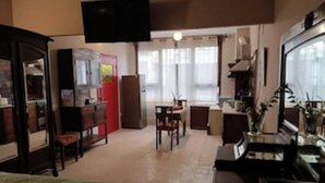 Une chambre d’hôtel de taille réduite, comprenant un lit, un bureau, une chaise, une télévision et une kitchenette.