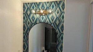 A bathroom with a white vanity, a large mirror, and a geometric patterned backsplash. - The Greenland Motel - Room No.2 (Munising)