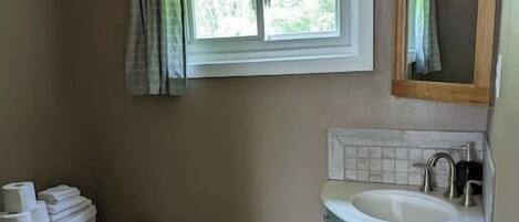 A bathroom with a toilet, sink, and window.