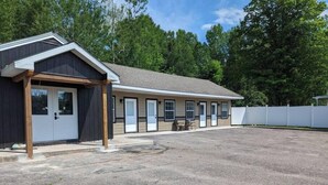 Un motel doté d’une entrée abritée, d’un parking et d’une rangée de chambres avec fenêtres.