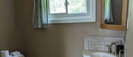 Un baño con inodoro, lavamanos y ventana.