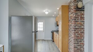 Een keuken met een bakstenen muur, een koelkast en houten keukenkastjes.