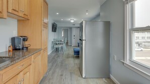 Een moderne keuken met houten kastjes, een granieten aanrechtblad, een roestvrijstalen koelkast en een eethoek met een tafel en stoelen.