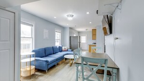 A modern living room with a blue sectional sofa, a round dining table, and a small side table. - Seaside Heights Apartment Near Beach + Boardwalk! (Seaside Heights)