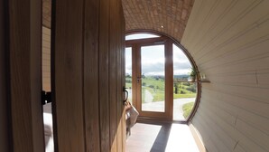 Vista desde una habitación con un amplio ventanal arqueado que da a un paisaje.