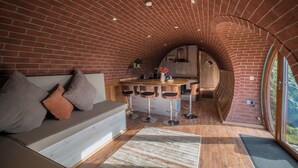 Una cocina acogedora con techo de arco de ladrillo, una barra de madera y una zona de estar con sofá y cojines.