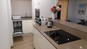 A modern kitchen with a built-in oven, a coffee maker, and a kettle on the counter. - RECONNECTAR Malgrat de Mar Garbí I (Malgrat de Mar)