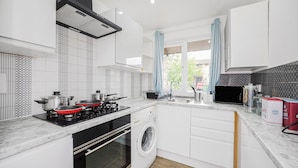 A modern kitchen with a built-in washing machine, a microwave, and a gas stove. - Verv London Stratford (London)