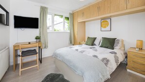 A bedroom with a bed, a desk, a TV, and a window with curtains. - Verv London Stratford (London)