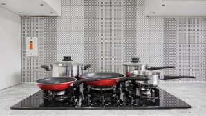 A kitchen with a gas stove, three pots, and a red frying pan on a black induction cooktop. - Verv London Stratford (London)