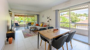 A modern living room with a dining area, large windows, and a balcony.