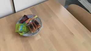 Una cocina con encimera de madera, una tetera, un tostador y un plato con aperitivos.
