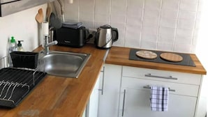 Cocina compacta con microondas, tostadora, hervidor y encimera de madera.