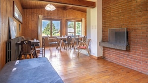 A wooden interior with a dining area, a TV mounted on a brick wall, and large windows. - Rustic chalet with garden in Chamonix (Chamonix-Mont-Blanc)