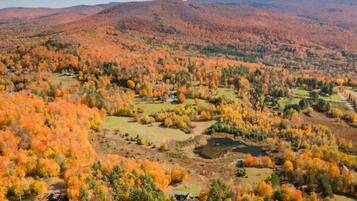 A rural landscape with autumn foliage, scattered houses, and rolling hills.