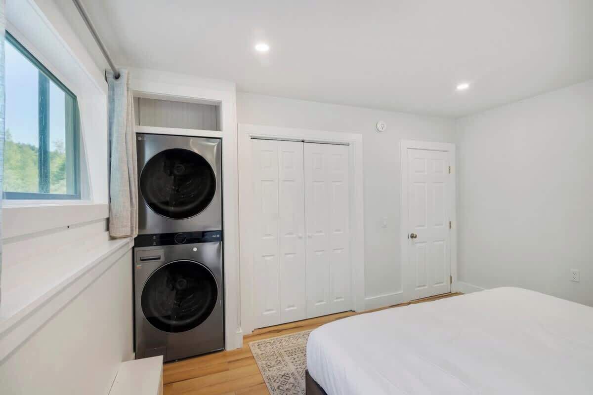 A bedroom with a bed, a washing machine, and a wardrobe.