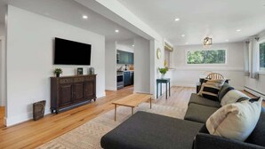 Una sala de estar moderna con un televisor de pantalla plana, muebles de madera oscura, un conjunto de sofá y una mesita.