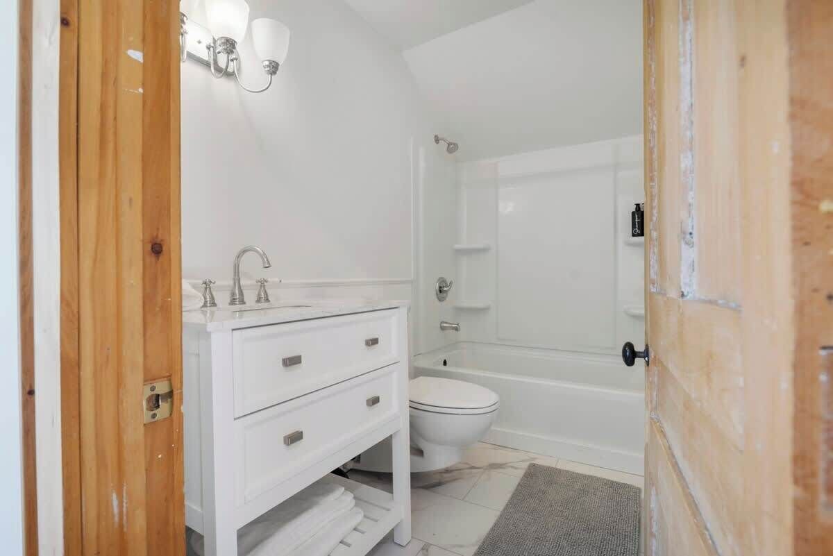 Un baño con tocador blanco, inodoro y bañera.