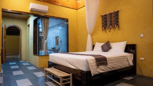 A bedroom with a bed, bench, and a bathroom visible through a glass door. - Ha Giang Wings Bungalow (Ha Giang 1)