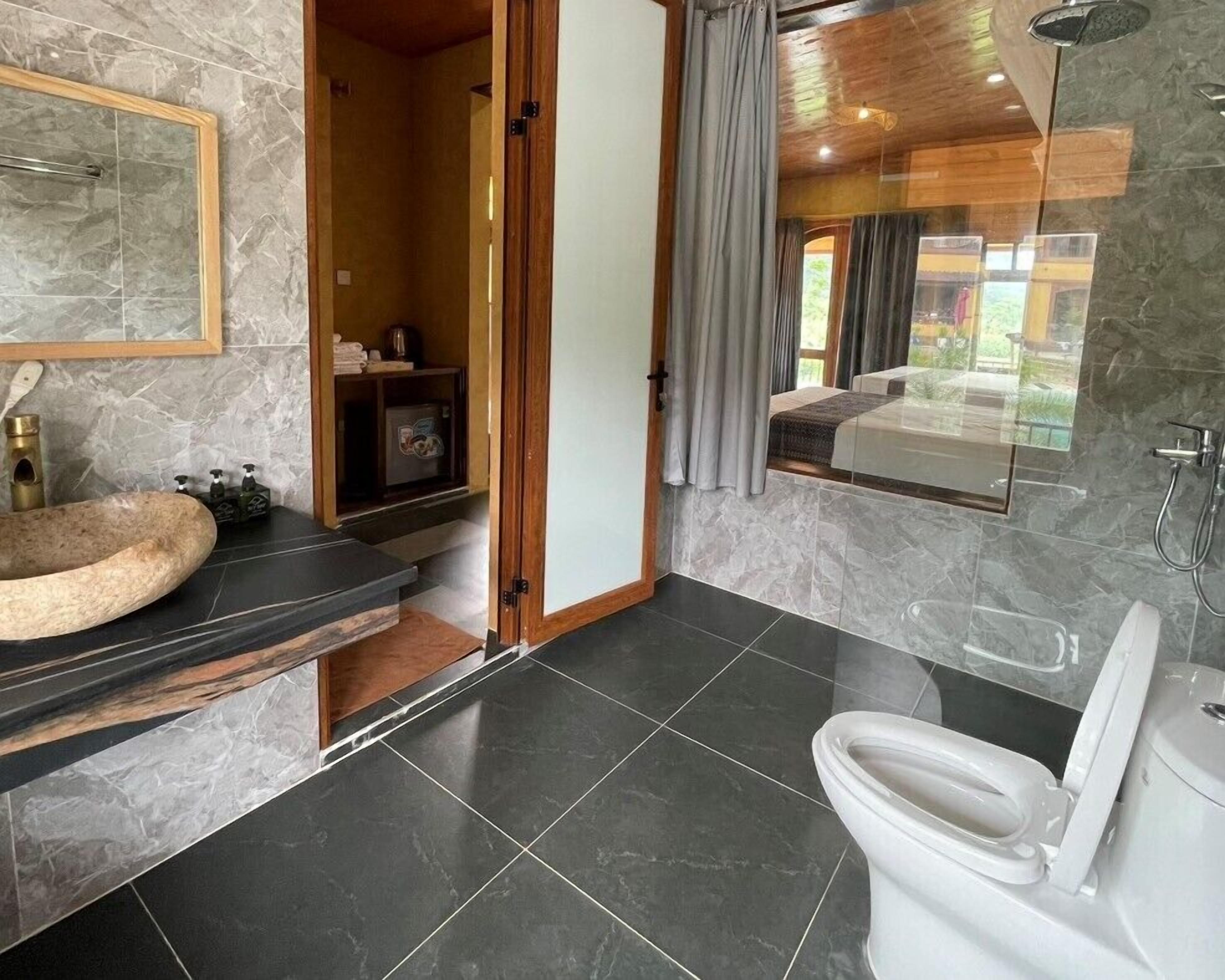 Une salle de bain moderne avec un lavabo en marbre, des toilettes et une douche.