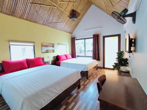 A hotel room with two beds, a wooden ceiling, a large window, and a desk with a chair.