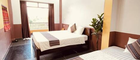 A hotel room with two beds, a large window, and a view of the outdoors.