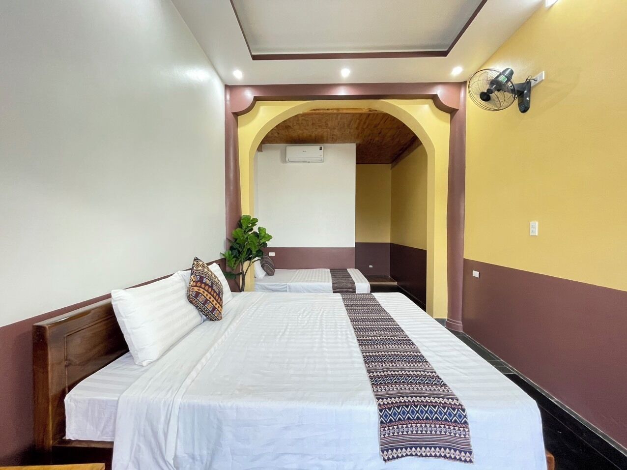 Une chambre d’hôtel avec deux lits, un ventilateur de plafond et un appareil de climatisation.
