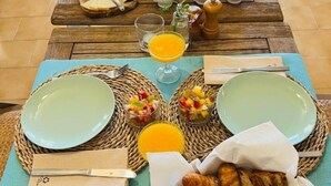 A breakfast setup with plates, bread, pastries, and a fruit bowl on a wooden table. - B&B Casa Mil Sueños (Ontinyent)