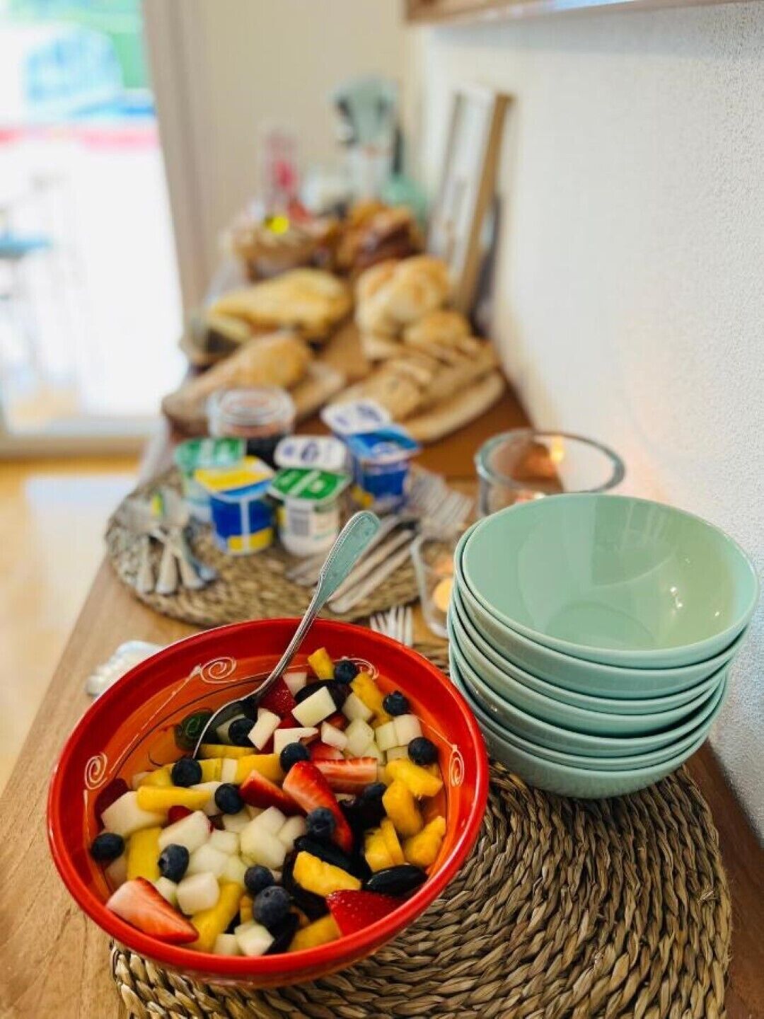 Um buffet de café da manhã com diversos alimentos e uma tigela de frutas mistas.