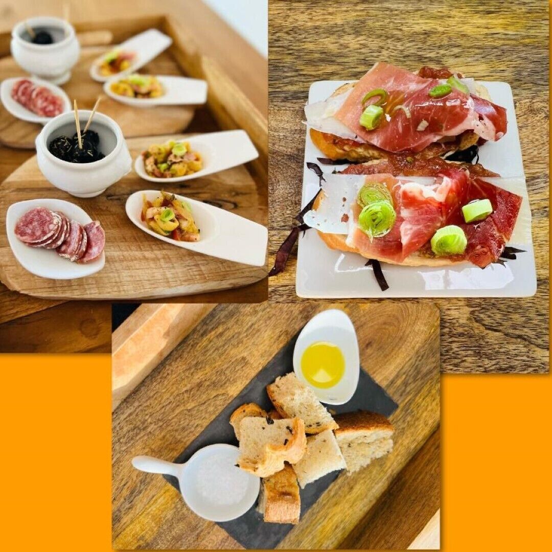 Een houten tafel met diverse etenswaren, zoals brood, vlees en sauzen.