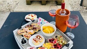 A picnic setup with a tray of food, a bottle of champagne, and a glass of red wine on a table outdoors. - B&B Casa Mil Sueños (Ontinyent)