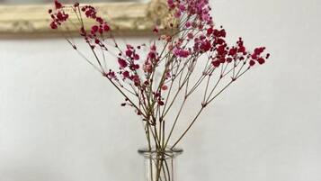 Un jarrón de vidrio transparente con flores rosadas sobre una mesa negra desgastada.