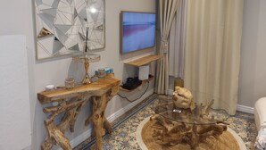 A modern living room with a wooden coffee table, a glass side table, a decorative mirror, a flat-screen TV, and a patterned floor. - L'étoile D'arras (Arras)