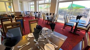 A restaurant with tables set for dining, large windows, and outdoor seating visible. - Tor Park Hotel (Torquay)