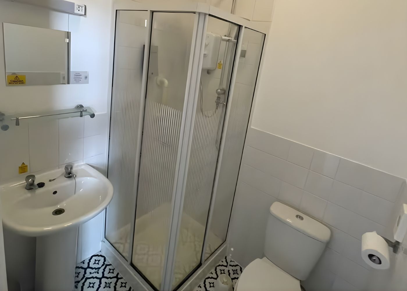 A bathroom with a glass shower enclosure, a sink, and a toilet.