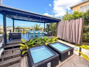 A rooftop terrace with a pool table, seating area, and two hot tubs.