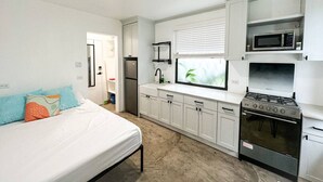 A compact kitchen with white cabinets, a microwave, a stove, and a sink. - Micro-Studio APT 5B, Oceanview + Pool, Near Beach | @ Paradise Point Barbados (Maxwell)