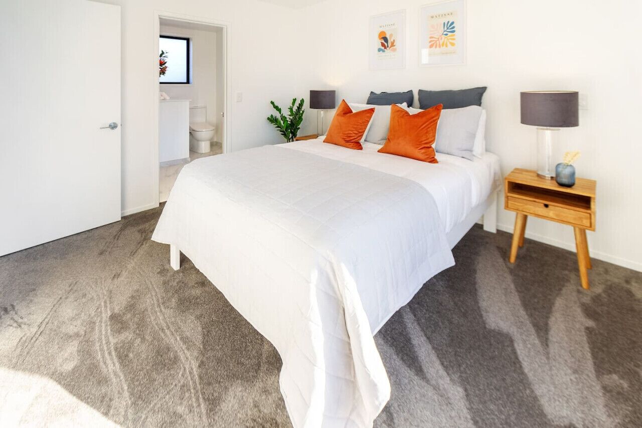 Un dormitorio con una cama grande, una mesita de noche, una lámpara y un cuadro enmarcado en la pared.