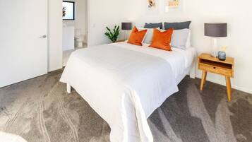 Un dormitorio con una cama grande, una mesita de noche, una lámpara y un cuadro enmarcado en la pared.