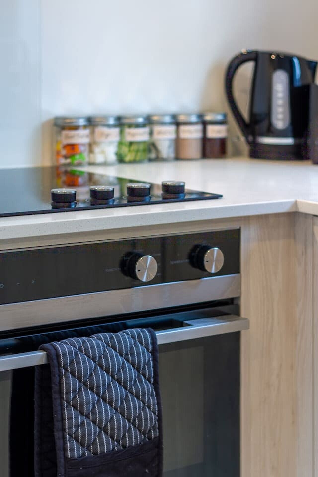 A kitchen with a stove, oven, and a kettle on the countertop.