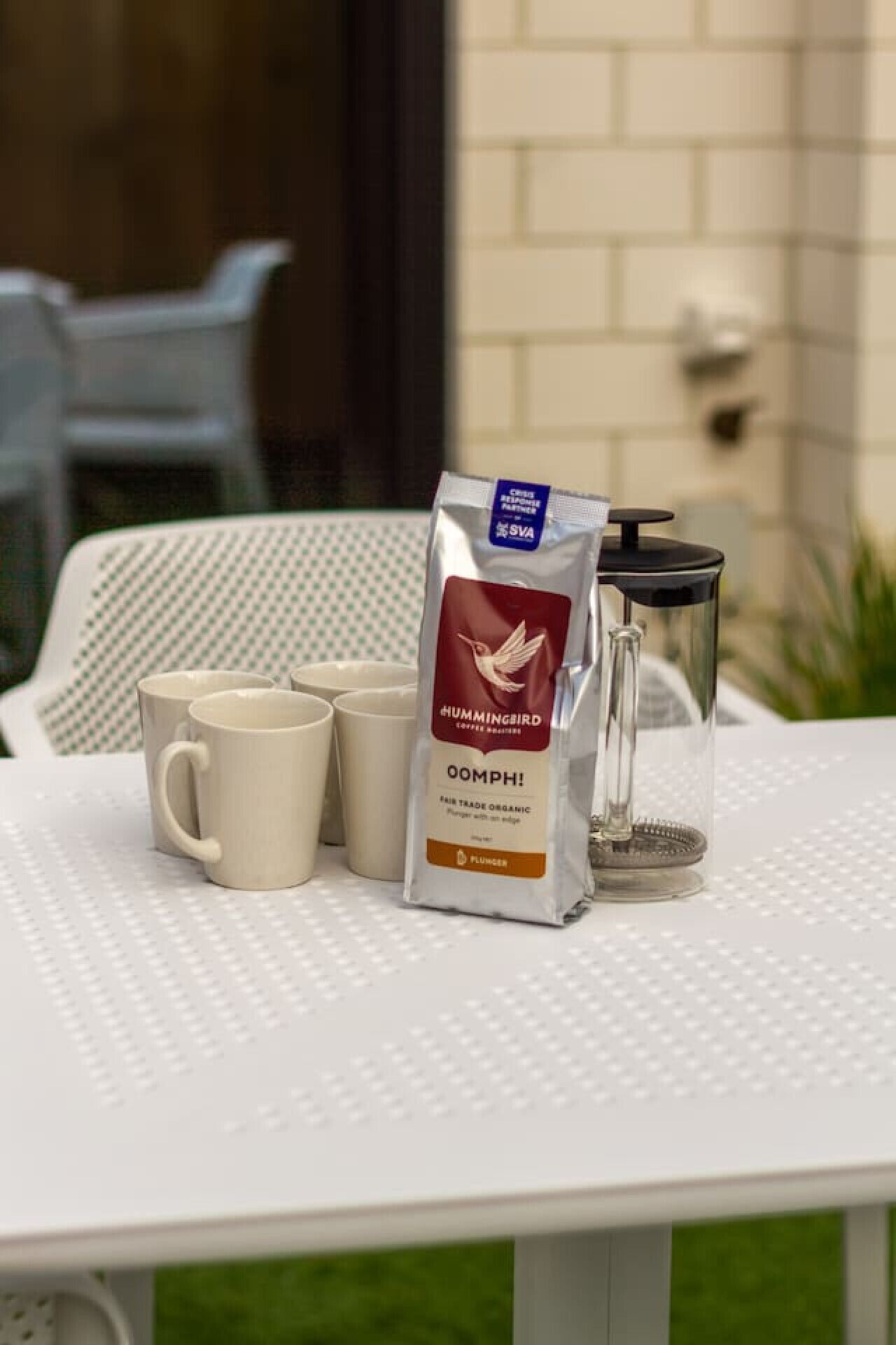 Una mesa con un molinillo de café, un paquete de café y varias tazas.