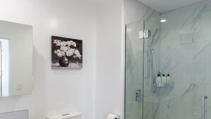 A modern bathroom with a toilet, vanity, and a glass-enclosed shower. - Large trendy 3 Bedroom Residence, Central City (Christchurch)