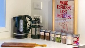 Een moderne keuken met een koffiezetapparaat, kruidenpotten en een inspirerende poster.