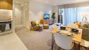 Una sala de estar moderna con comedor, televisor y cocina.