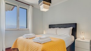 Hotellihuone, jossa on sänky, yöpöytä, ikkuna ja näkymä taivaalle.