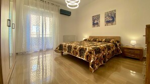 A bedroom with a bed, bedside table, lamp, and artwork on the wall.