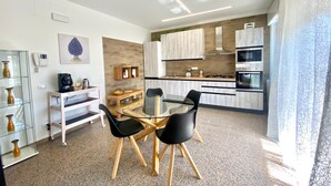 A modern kitchen with wooden cabinets, a gas stove, and a built-in oven. There is a dining area with a glass table and black chairs.