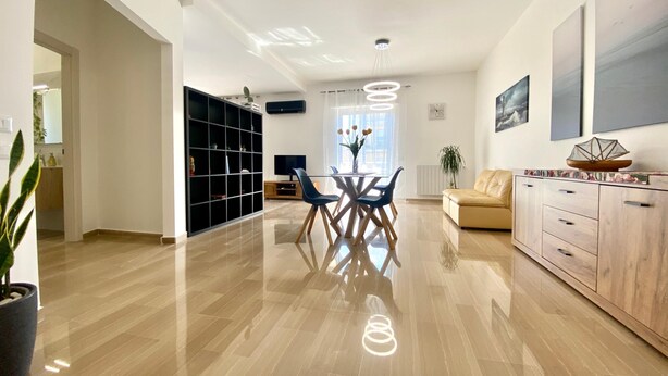 A spacious living area with a dining table, chairs, a sofa, and a cabinet.