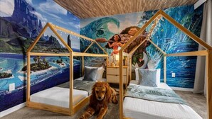 Una habitación con dos camas, un mural y un perro.