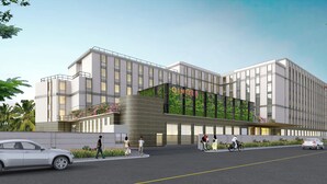 Ein modernes Hotel mit großer Glasfassade, einer gut sichtbaren Beschilderung und einem begrünten Eingangsbereich.